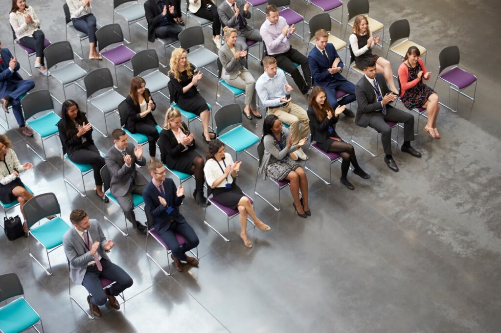 Overhead View Of Audience Applauding Speaker At Conference